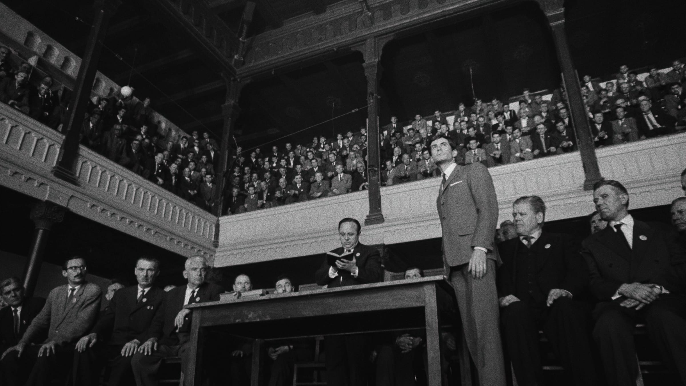 Een man staat alleen voor een groot publiek